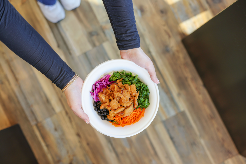 Hands holding a BIBIBOP healthy bowl, a high protein lunch option in Cincinnati, Ohio