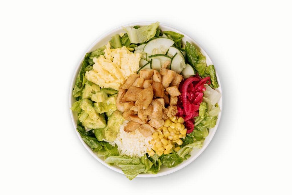 BIBIBOP's Avo Cobb Salad with Chicken, Crispy Romaine, Avocado, Pickled Red Onion, Cucumber, Corn, Egg, and Cheese, finished with your choice of sauce. 