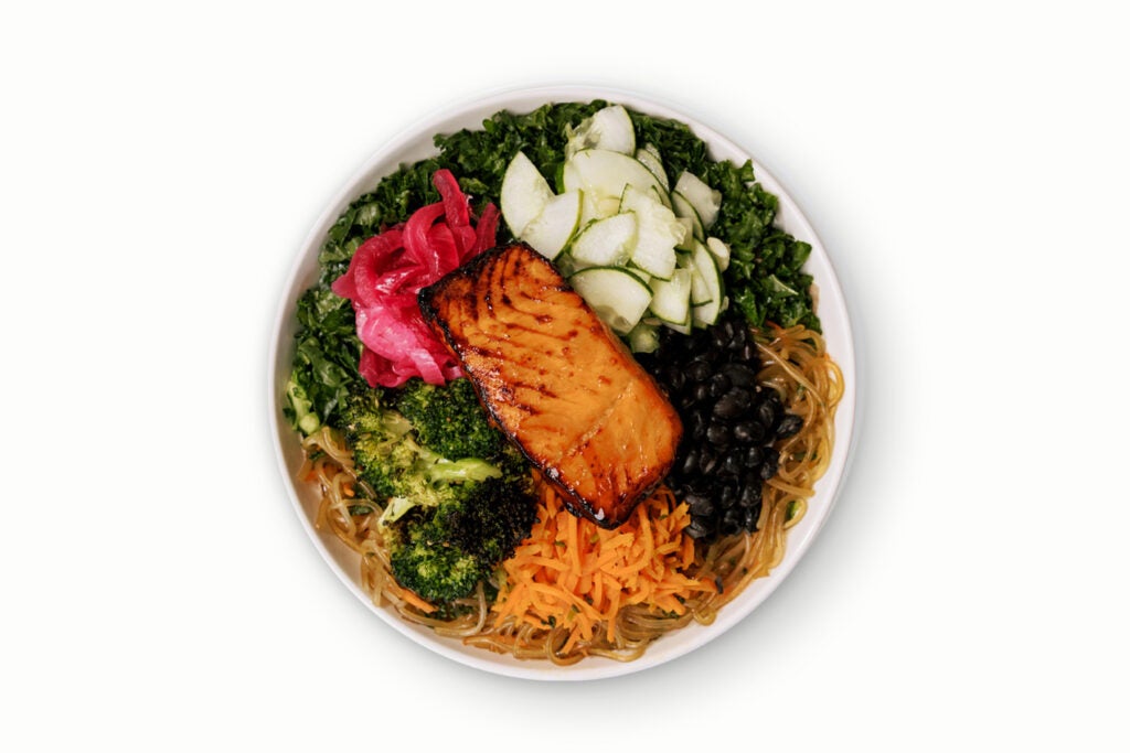 BIBIBOP's Nourish Bowl with Miso Glazed Salmon, Honey Citrus Kale, Sweet Potato Noodles, Roasted Sesame Broccoli, Black Beans, Carrots, Cucumber, and Pickled Red Onion, finished with Sesame Oil.
