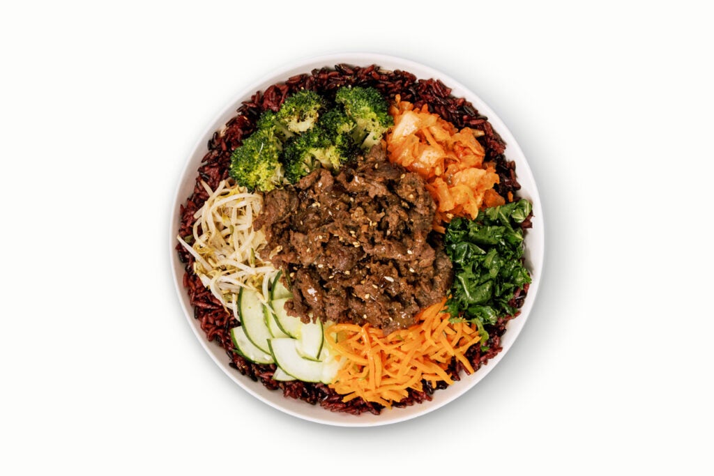 BIBIBOP's Seoul Bowl with Korean BBQ Beef, Purple Rice, Bean Sprouts, Roasted Sesame Broccoli, Honey Citrus Kale, Carrots, Cucumber, and Kimchi, topped with spicy Gochujang sauce