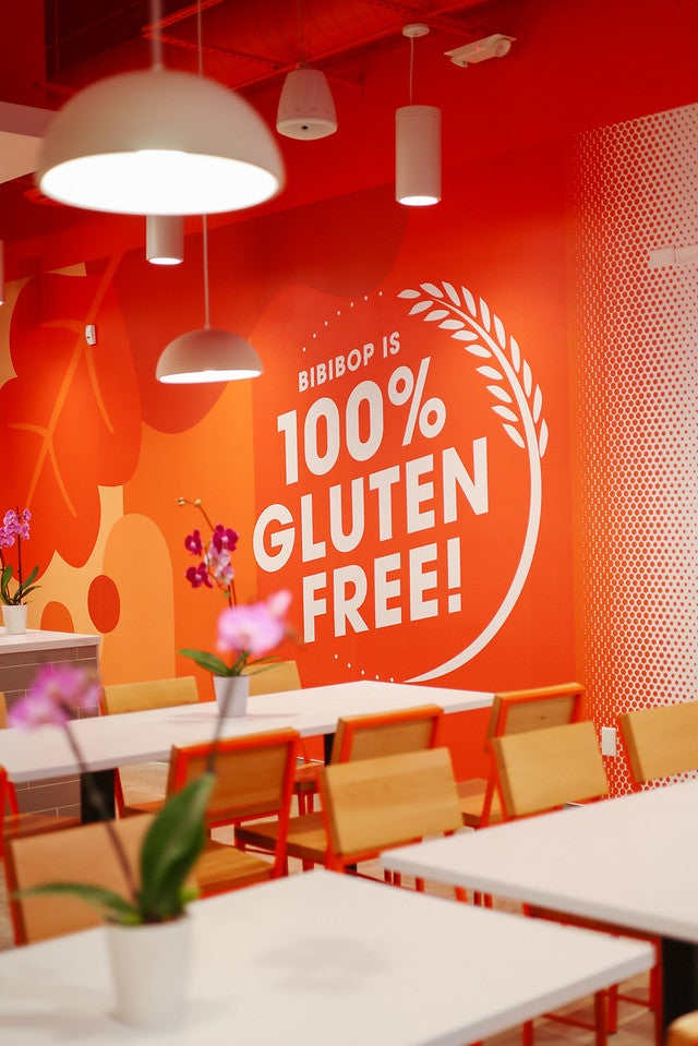 The 100% Gluten Free wall graphic inside a BIBIBOP Asian Grill dining room