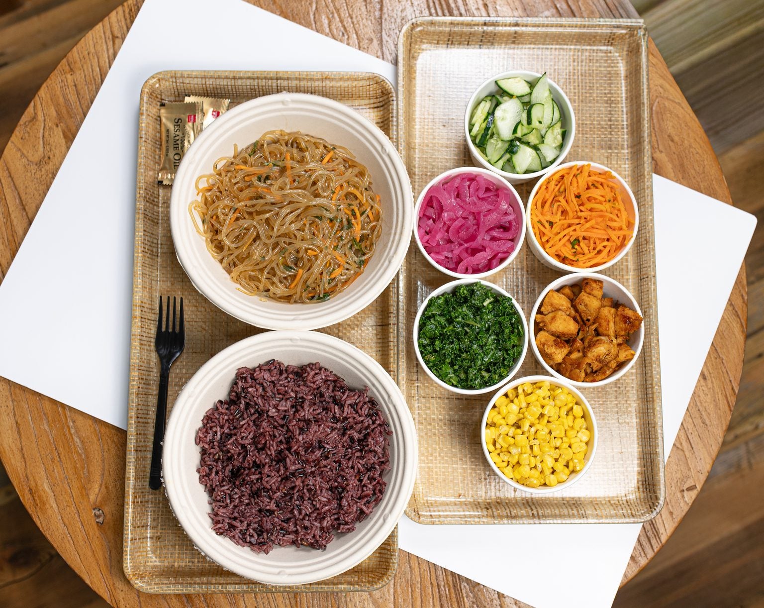 Purple Rice and noodles served with Cucumber, Pickled Red Onion, Carrots, Kale and Corn in separate cups